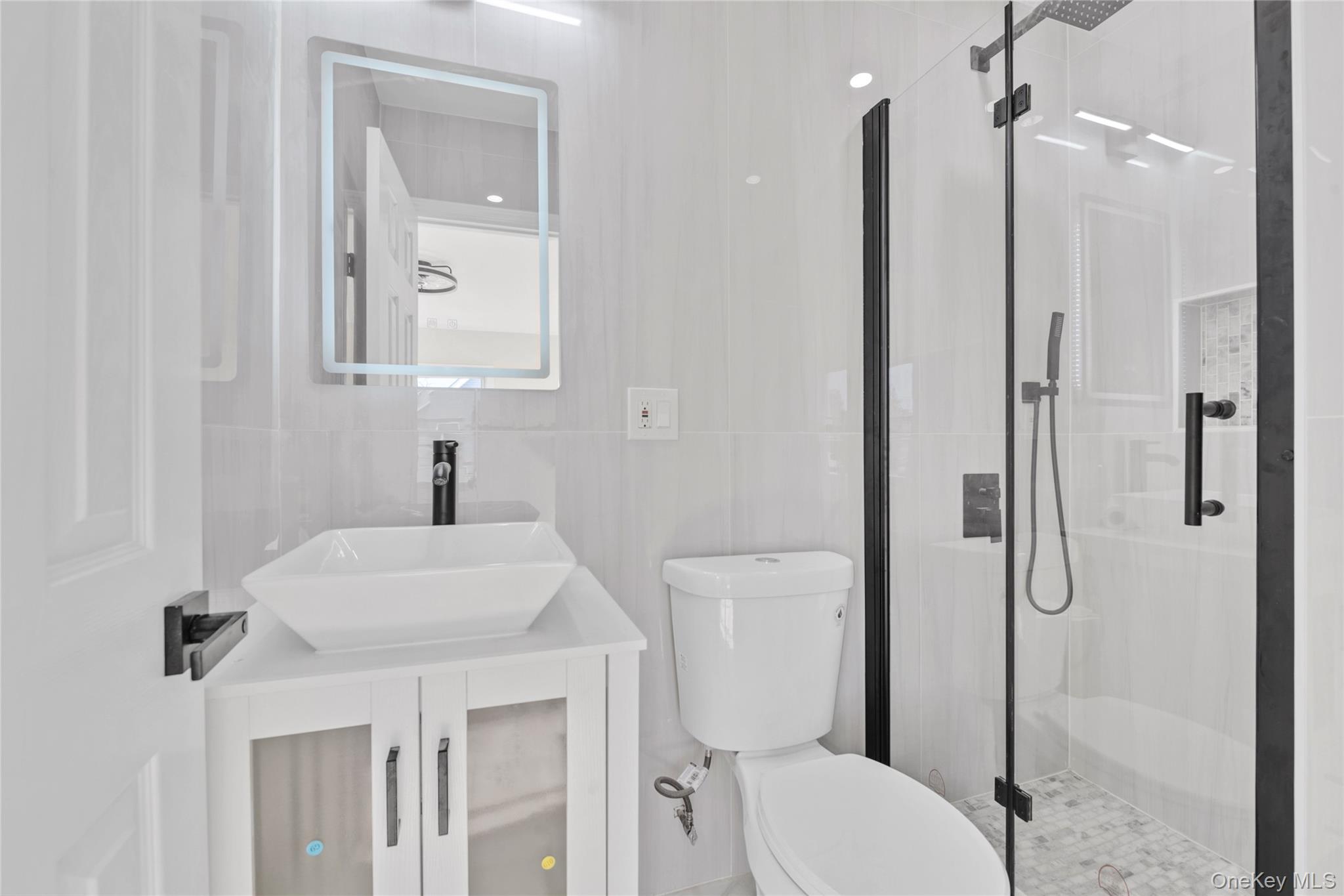 220-27 134th Road Queens, NY 11413 - Photo 11 of 22 Full bathroom featuring a shower stall, vanity, and tile walls