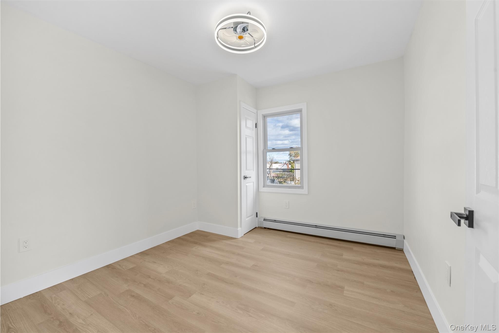 220-27 134th Road Queens, NY 11413 - Photo 13 of 22 Empty room with a baseboard heating unit and light wood-style floors