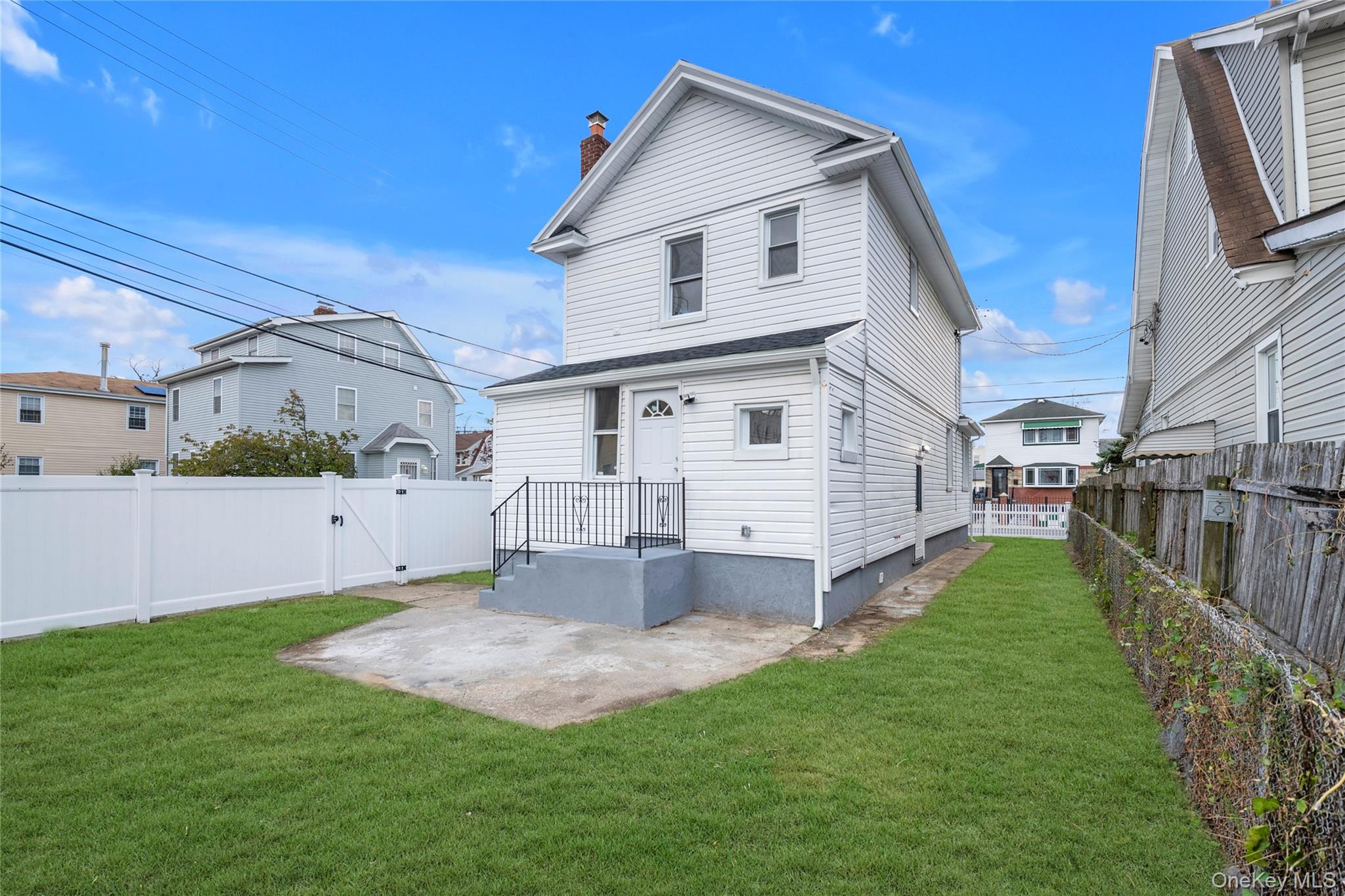 220-27 134th Road Queens, NY 11413 - Photo 18 of 22 Back of property with a chimney, a fenced backyard, a patio area, and a gate