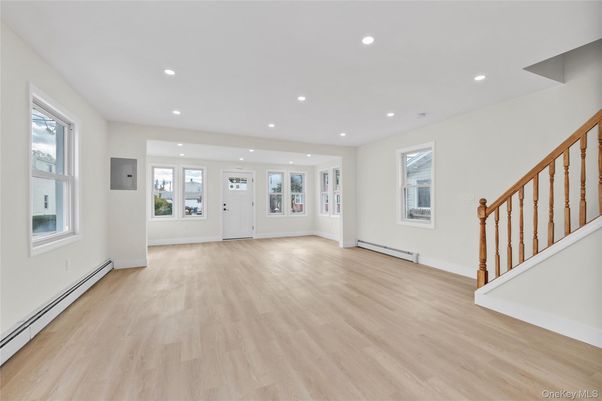 220-27 134th Road Queens, NY 11413 - Photo 2 of 22 Unfurnished living room with baseboard heating, recessed lighting, light wood-style floors, stairs, and plenty of natural light