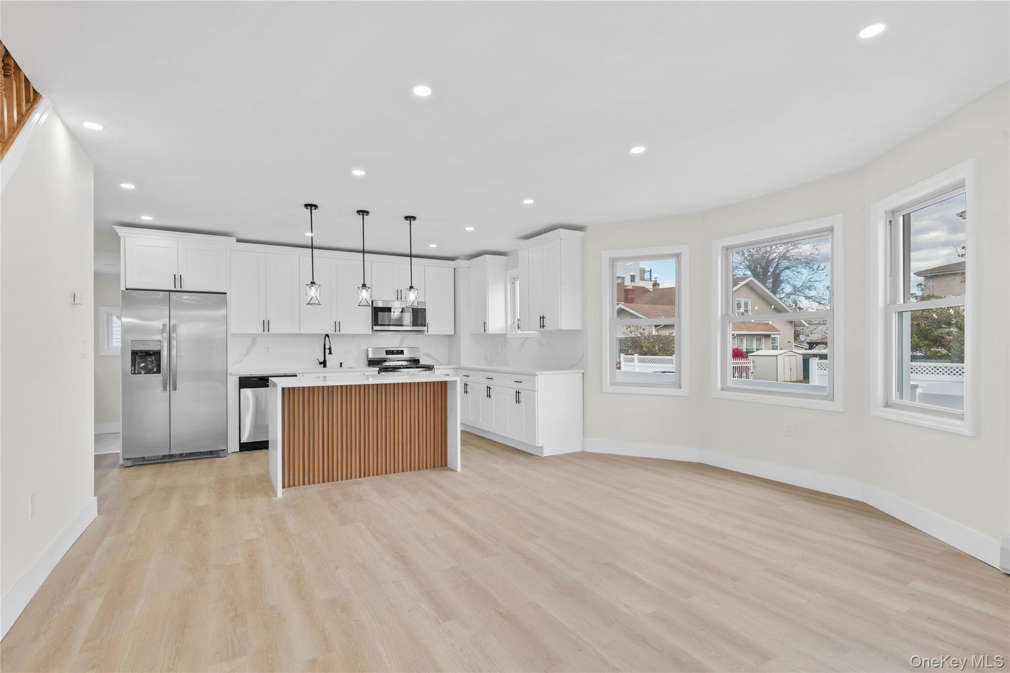 220-27 134th Road Queens, NY 11413 - Photo 4 of 22 Kitchen with appliances with stainless steel finishes, white cabinets, a center island, light wood-style floors, and decorative light fixtures