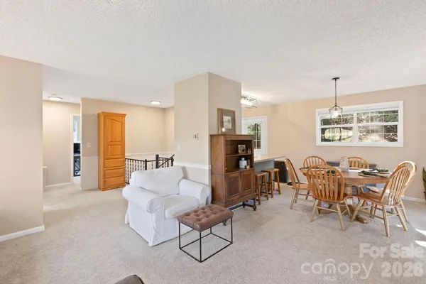 a living room with furniture and a dining table with kitchen appliances