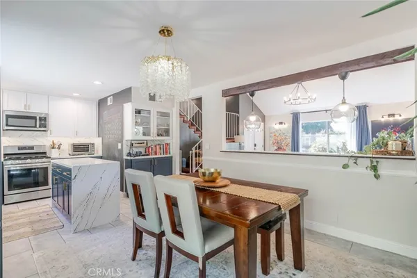 a view of a dining room with furniture a chandelier and kitchen view