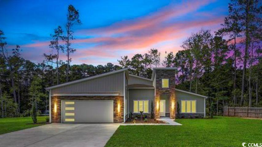 View of front facade with driveway, stone siding, and an attached garage
