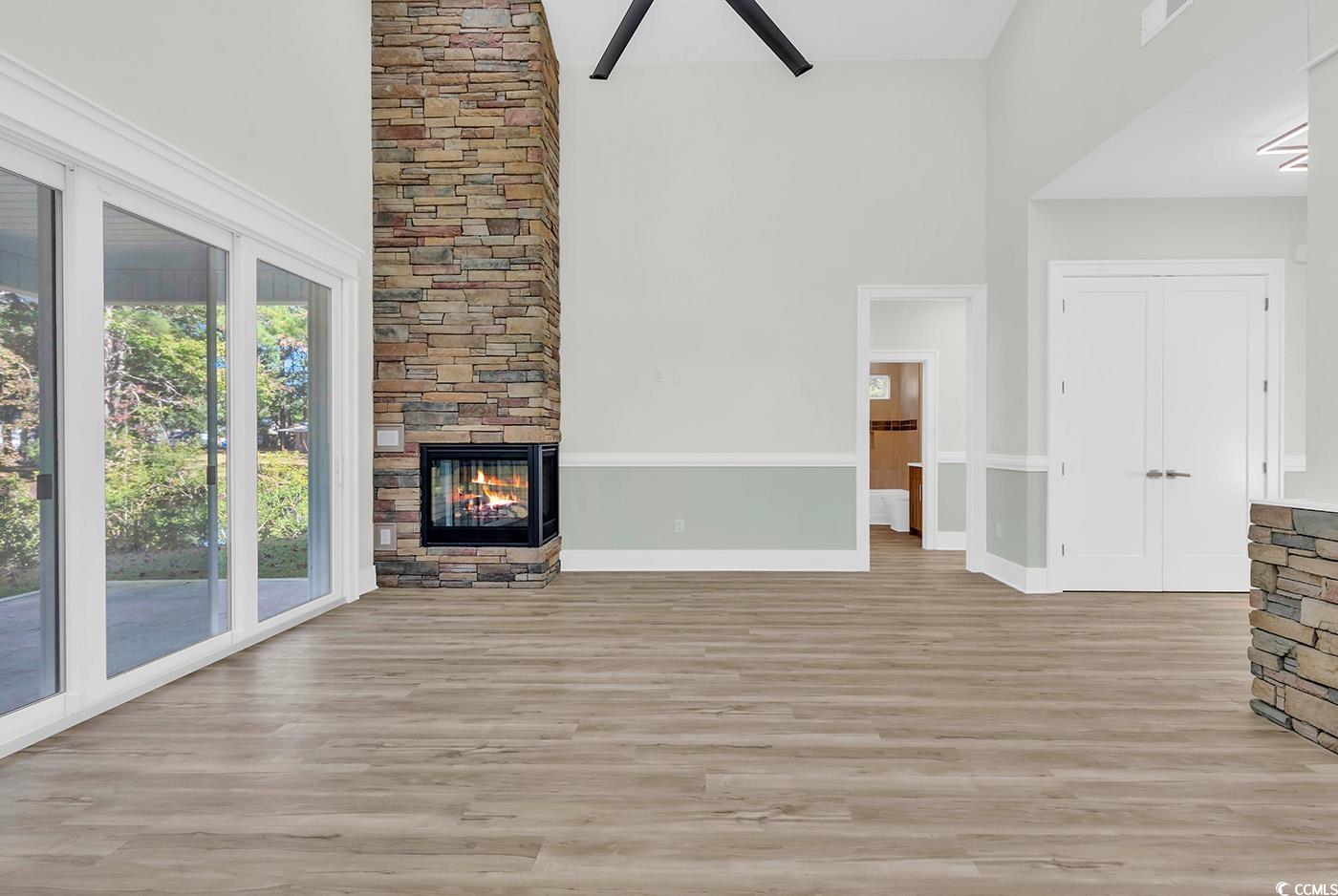 1028 Colette Court Conway, SC 29526 - Photo 8 of 39 Unfurnished living room with a towering ceiling, light wood-type flooring, a ceiling fan, and a stone fireplace