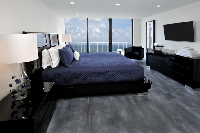 a large bed sitting in a bedroom next to a window with flat screen tv