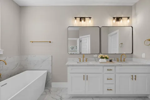 a bathroom with a double vanity sink a mirror and a bathtub