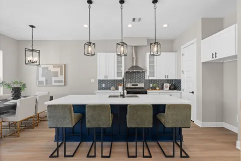 a kitchen with stainless steel appliances a dining table chairs and white cabinets
