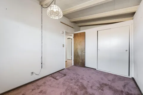a view of an empty room with a chandelier fan