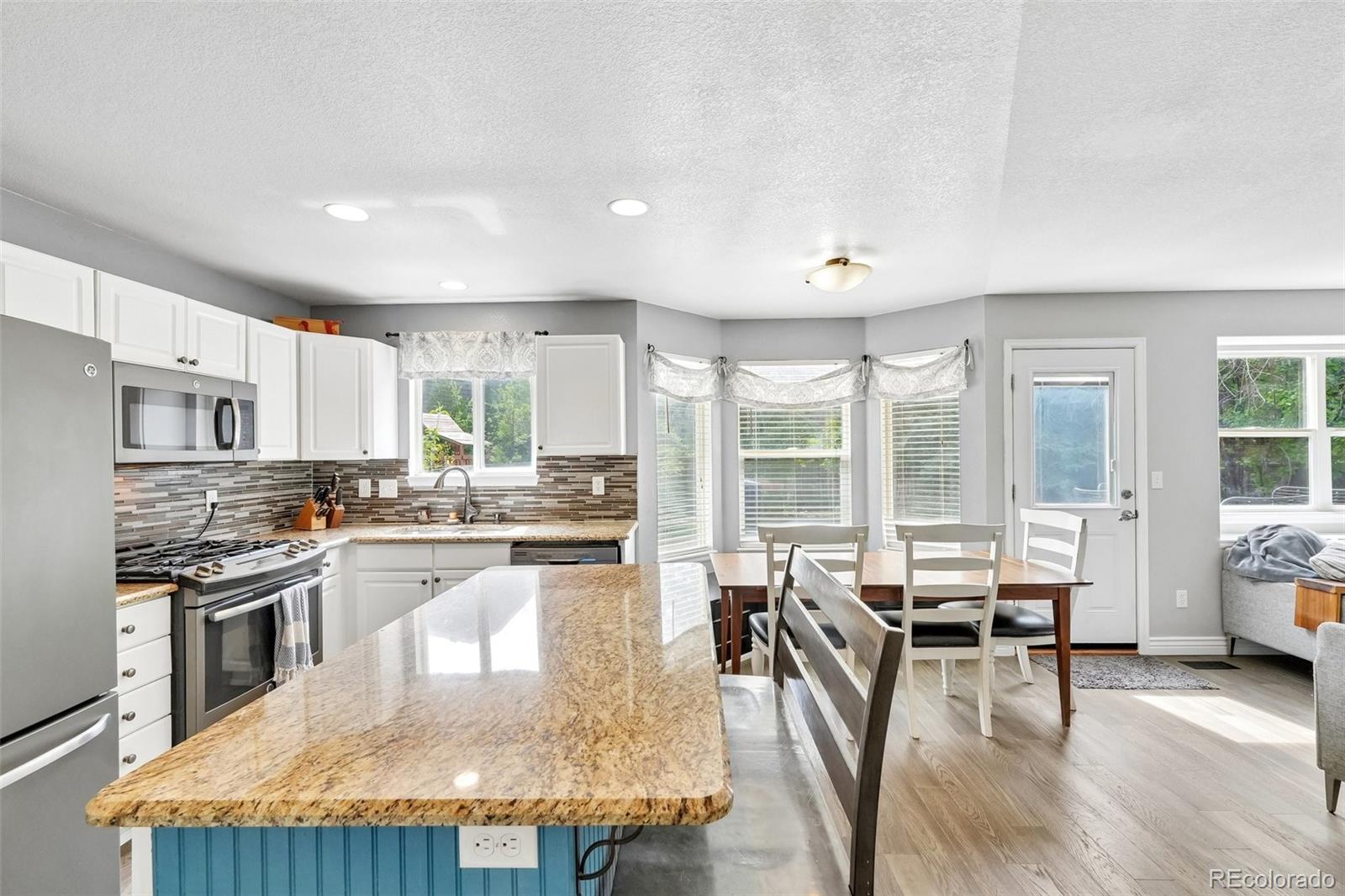 6642 Tiger Tooth Lone Tree, CO 80124 - Photo 18 of 44 a kitchen with stainless steel appliances granite countertop a stove top oven a refrigerator a dining table and chairs with wooden floor