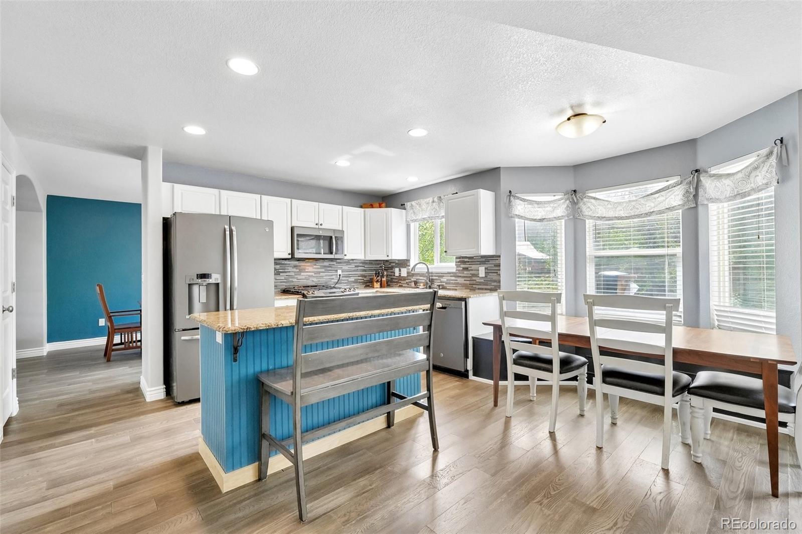 6642 Tiger Tooth Lone Tree, CO 80124 - Photo 19 of 44 a kitchen with stainless steel appliances refrigerator wooden floor dining table and chairs
