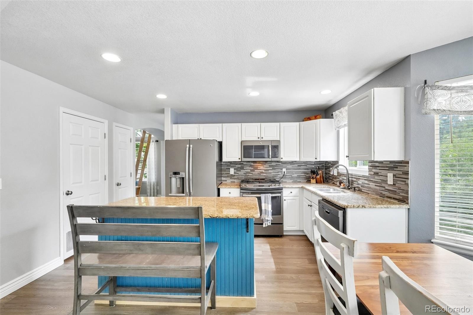 6642 Tiger Tooth Lone Tree, CO 80124 - Photo 20 of 44 a kitchen with stainless steel appliances kitchen island granite countertop a stove top oven a sink dishwasher and a refrigerator with wooden floor
