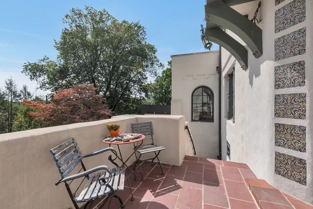 a view of a small yard in front of a house with large trees and plants