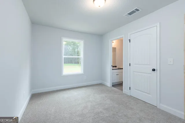 a view of an empty room with a window and a bathroom