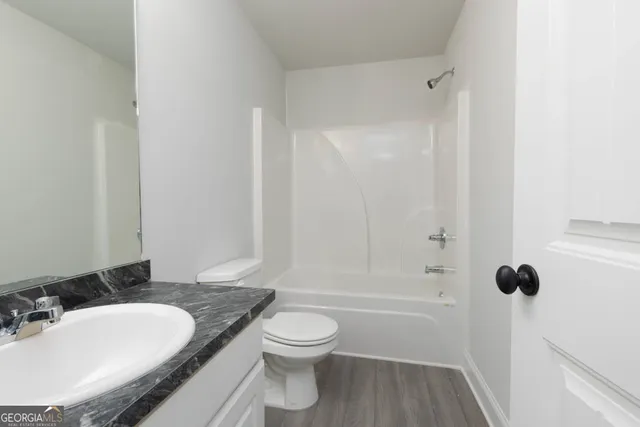 a bathroom with a granite countertop sink toilet a mirror and shower