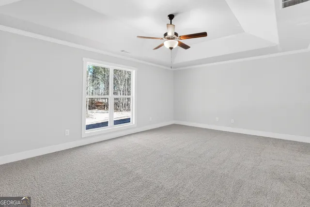 an empty room with chandelier fan and windows