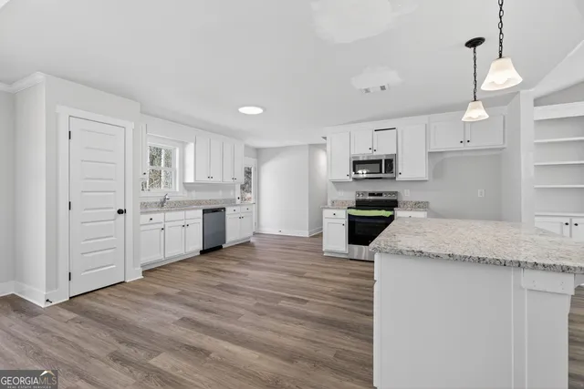 a large kitchen with cabinets wooden floor and stainless steel appliances