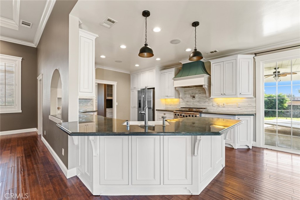 5836 Buckthorn Avenue Rancho Cucamonga, CA 91737 - Photo 48 of 63 a large kitchen with stainless steel appliances kitchen island granite countertop a large counter top a stove a chimney a sink and cabinets