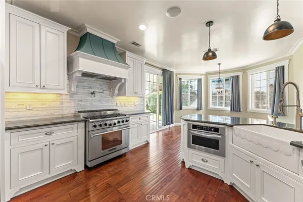 a large kitchen with granite countertop a large kitchen island white cabinets and stainless steel appliances