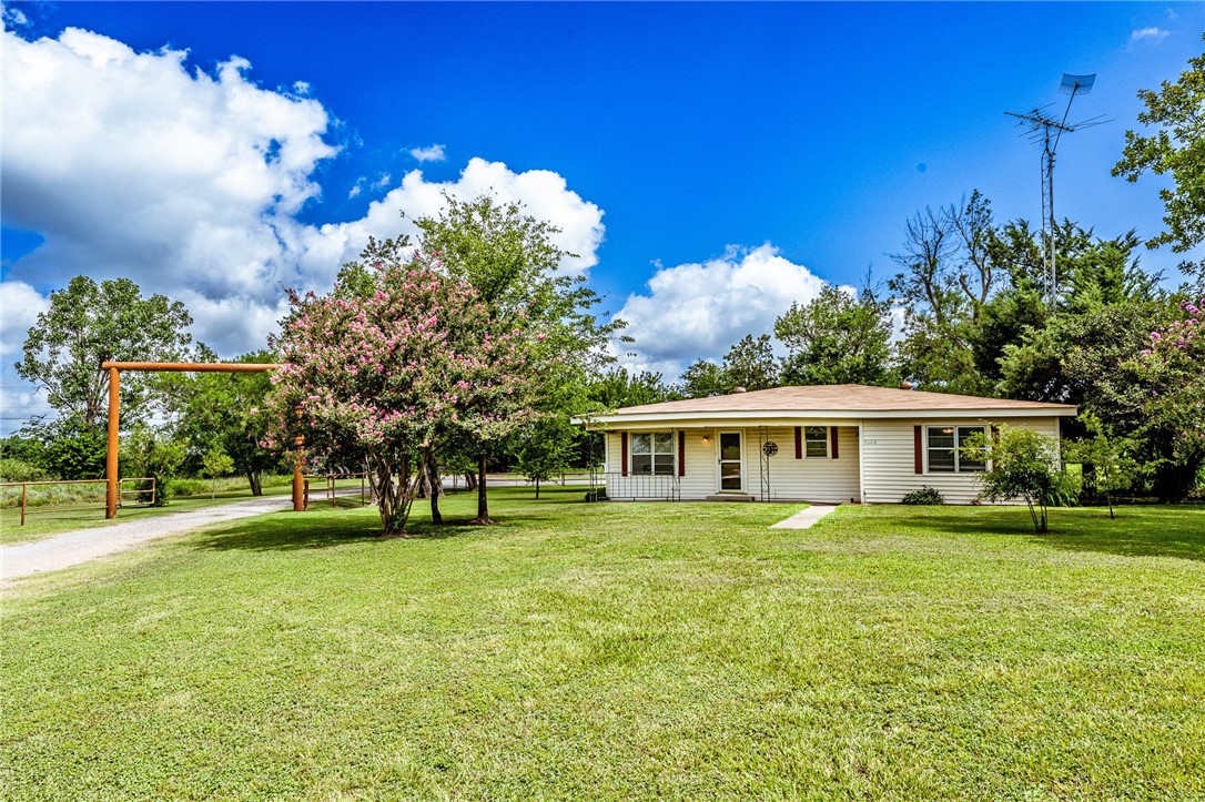 View of front of property featuring a front yard and gravel driveway