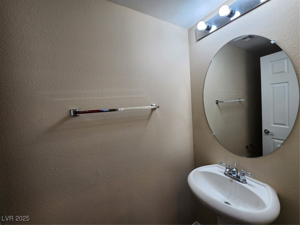 9409 Crimson Sky Street Las Vegas, NV 89178 - Photo 13 of 46 Half bathroom featuring a textured wall and a sink