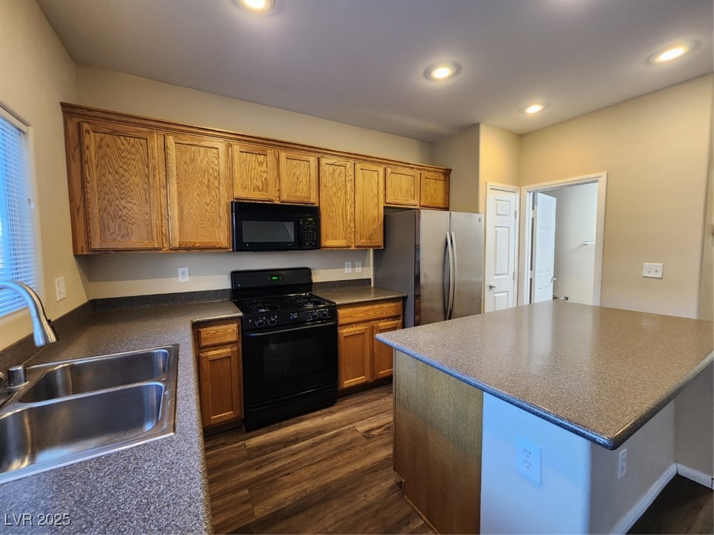 9409 Crimson Sky Street Las Vegas, NV 89178 - Photo 9 of 46 Kitchen featuring stove, brown cabinetry, stainless steel microwave, black refrigerator, and dark wood-type flooring