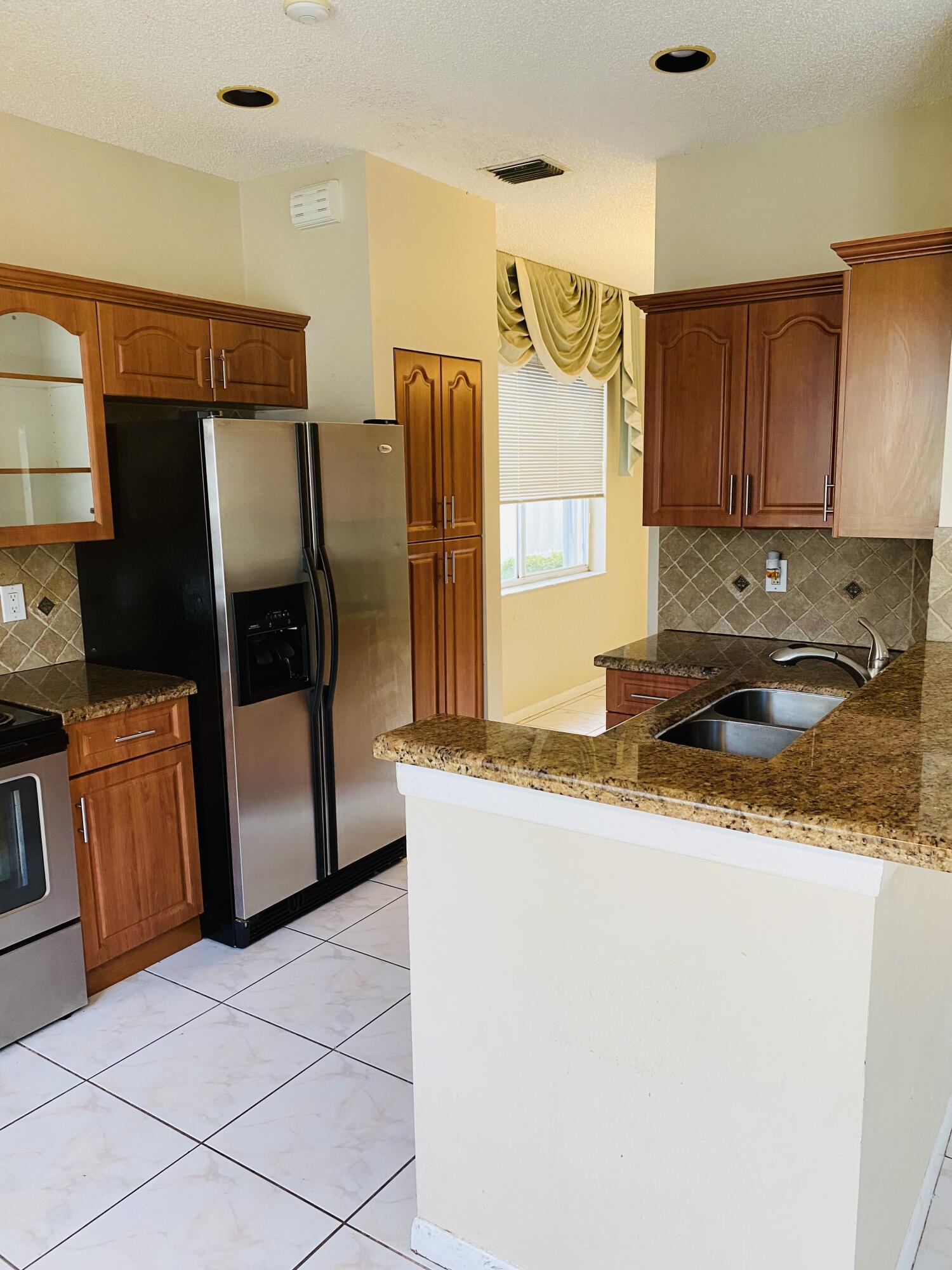 439 Talavera Road Weston, FL 33326 - Photo 3 of 17 a kitchen with granite countertop a refrigerator and a stove top oven