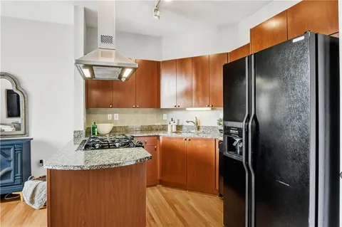a kitchen with stainless steel appliances granite countertop a refrigerator a stove and a sink with wooden floor