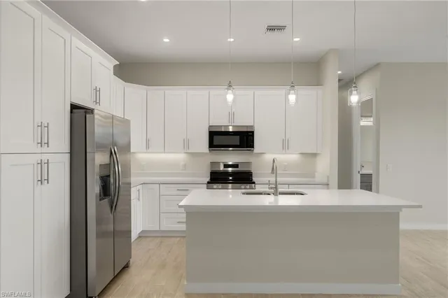 a kitchen with kitchen island stainless steel appliances a refrigerator a sink a stove a microwave and cabinets