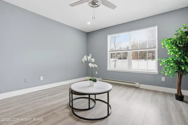 a view of an empty room with wooden floor and a ceiling fan