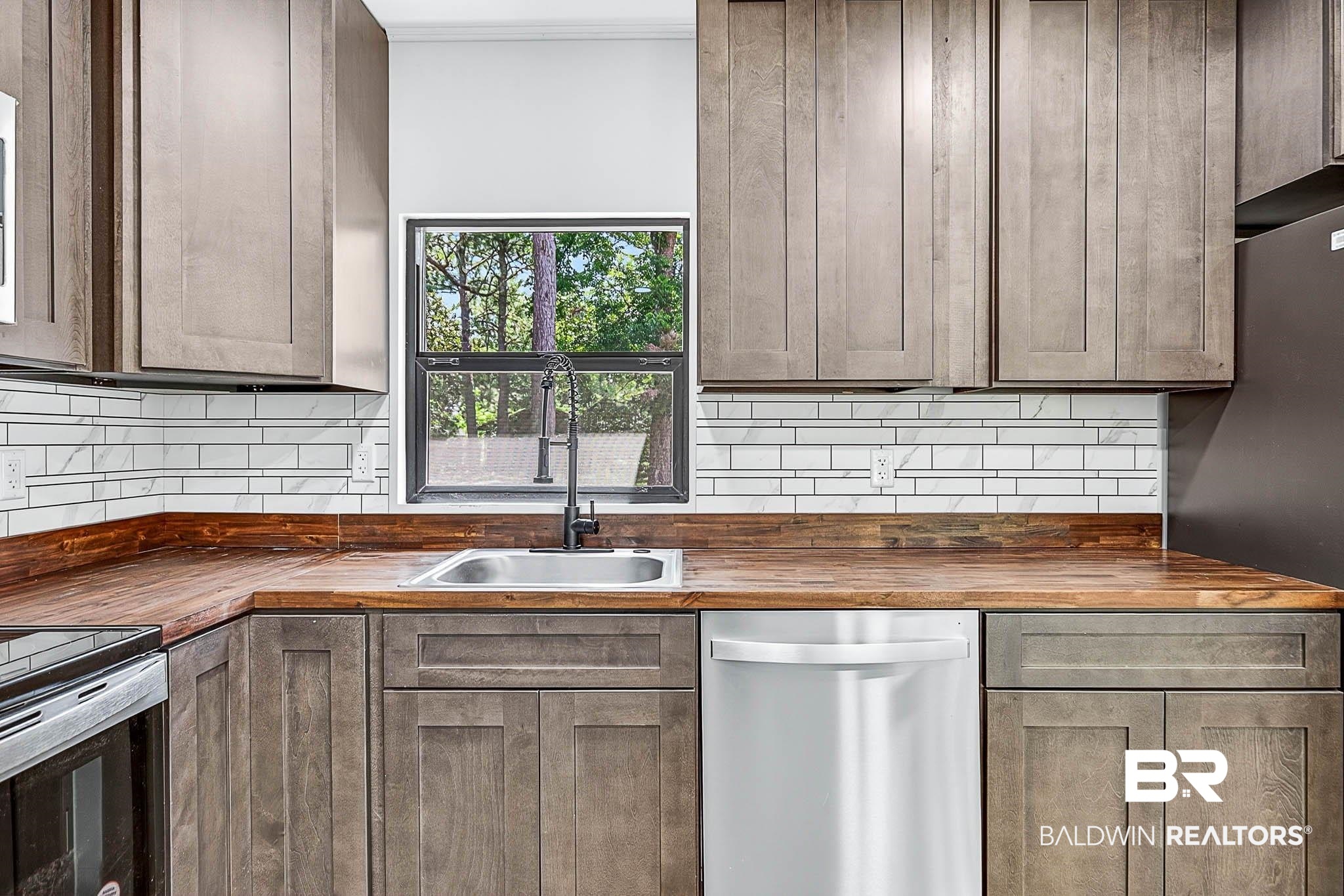 101 Terry Avenue Brewton, AL 36426 - Photo 32 of 48 Kitchen featuring wooden counters, stainless steel dishwasher, decorative backsplash, and freestanding refrigerator