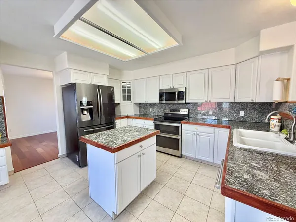 a kitchen with stainless steel appliances granite countertop a refrigerator stove microwave and sink