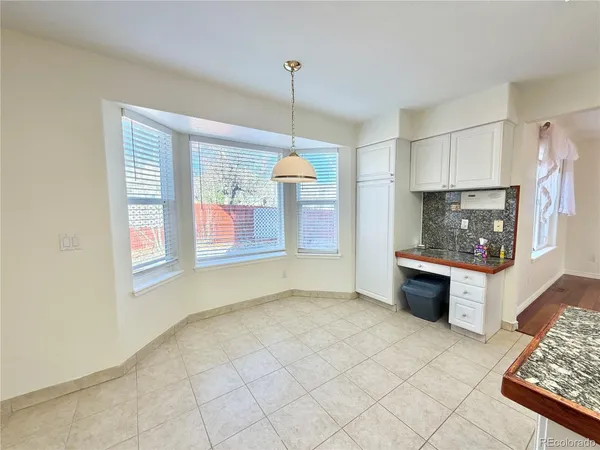 a view of an empty room with kitchen and window