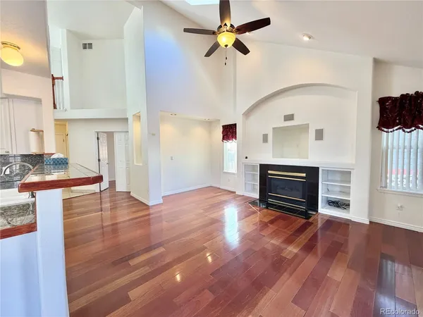a view of empty room with wooden floor and fan