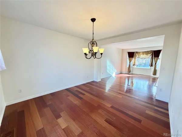 a view of a room with wooden floor chandelier and windows
