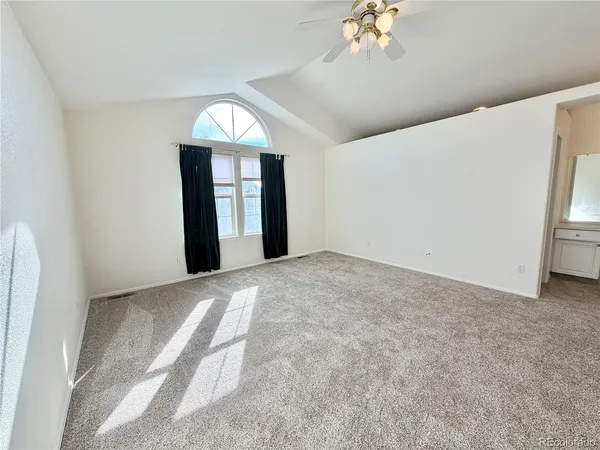 an empty room with a chandelier fan and windows