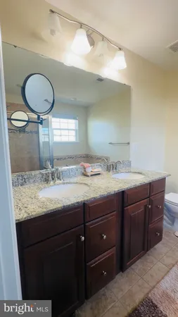 a bathroom with a granite countertop sink a toilet and a mirror