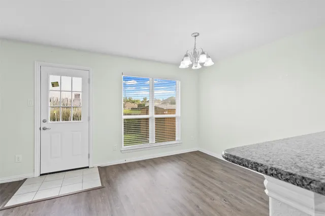 an empty room with wooden floor cabinet and windows