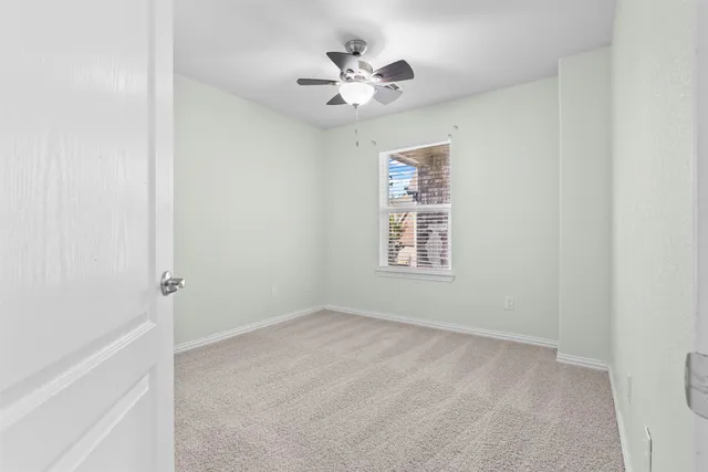 an empty room with a window and a ceiling fan