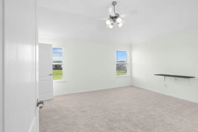 an empty room with windows and chandelier fan