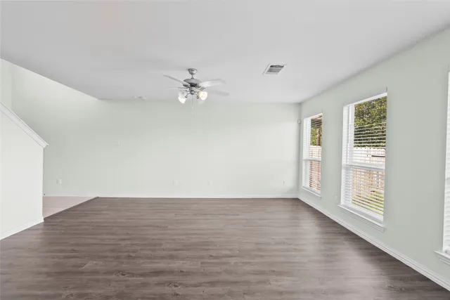 a view of an empty room with a window and wooden floor