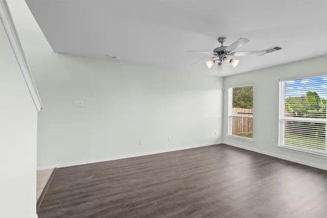 a view of an empty room with a window and wooden floor