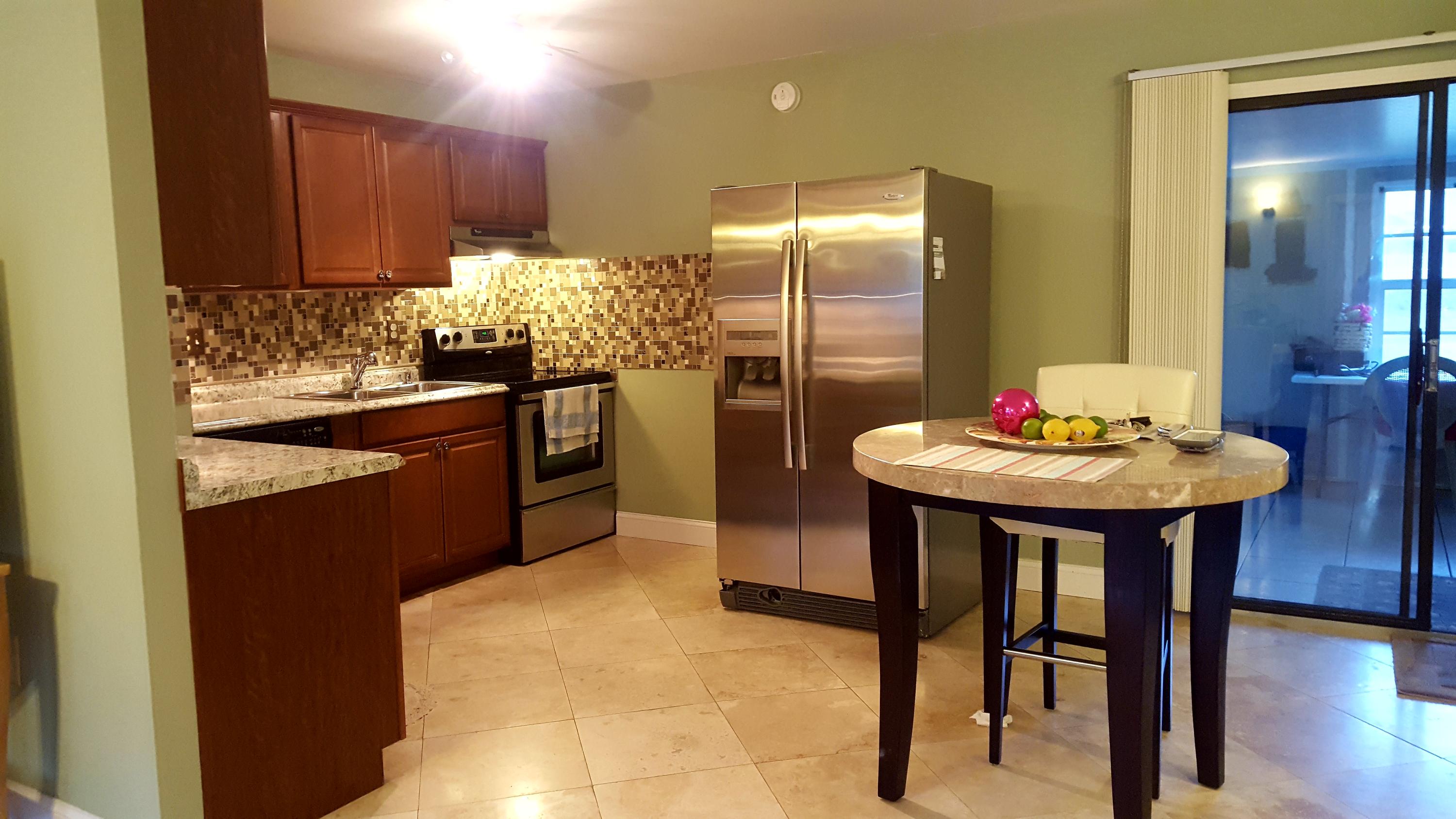 17999 41st Road North Loxahatchee, FL 33470 - Photo 10 of 19 a kitchen with stainless steel appliances kitchen island granite countertop a table chairs and a refrigerator