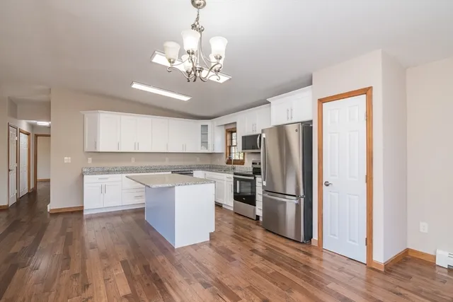 a view of a kitchen with a refrigerator wooden floor and a ceiling fan