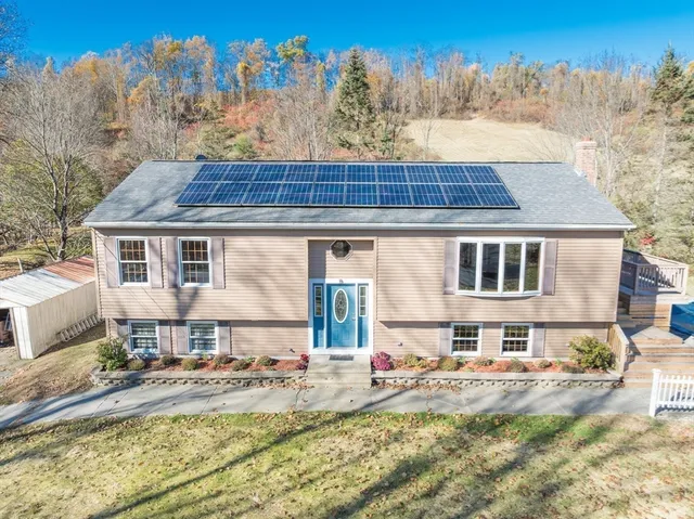 a front view of house with yard and trees in the background