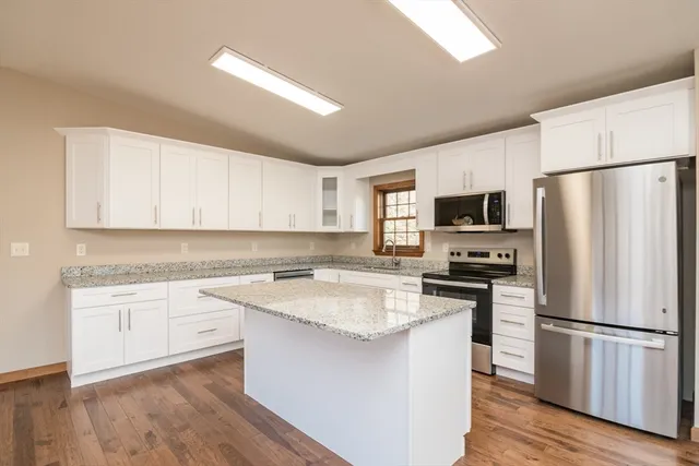 a kitchen with a refrigerator a sink and wooden floor
