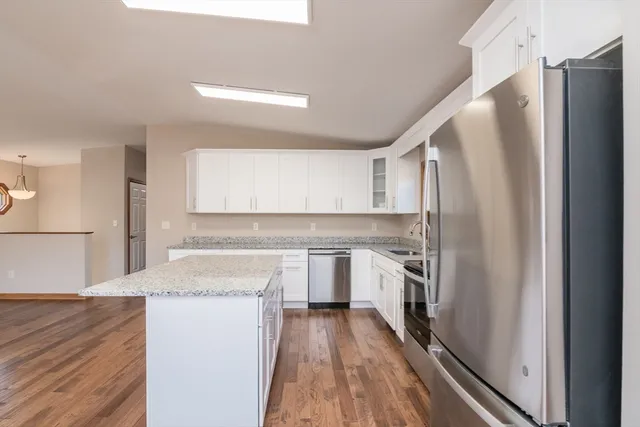 a large kitchen with a center island wooden floor stainless steel appliances and cabinets
