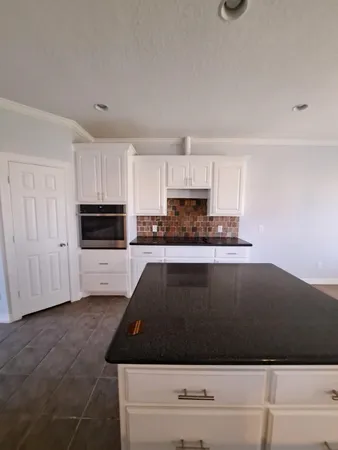 a kitchen with granite countertop white cabinets and black appliances