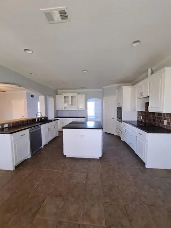 a large kitchen with stainless steel appliances a large counter top a stove and a refrigerator