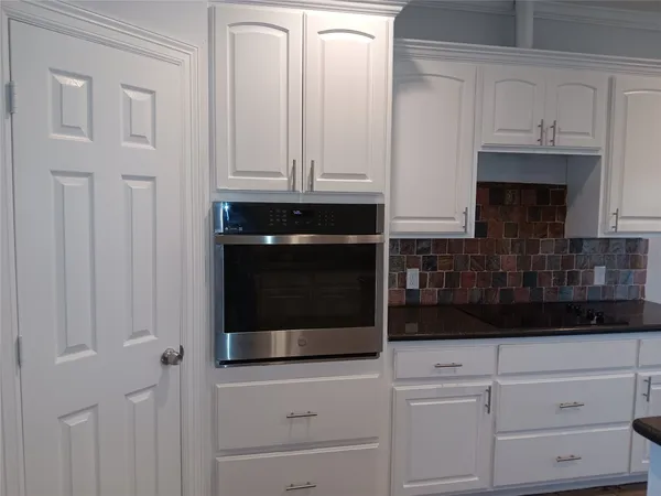 a kitchen with white cabinets and black appliances